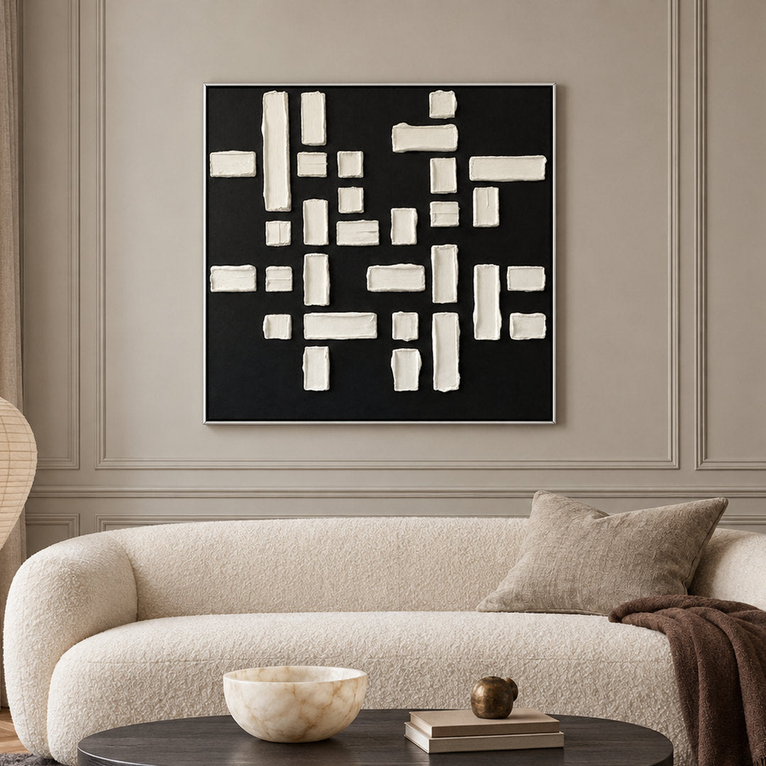 black and white geometric textured wall art with raised blocks displayed in a styled living room