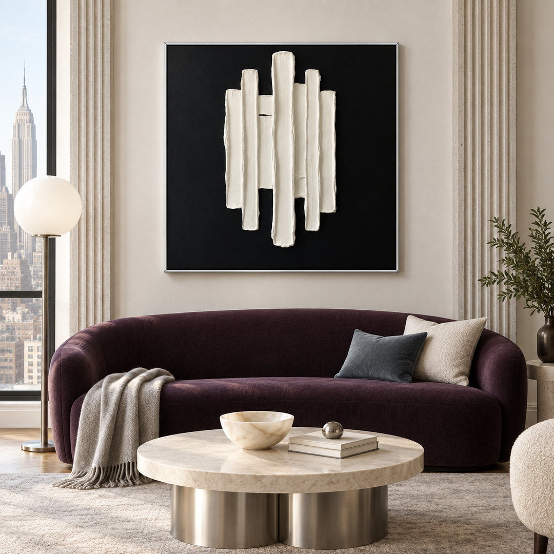black and white sculptural wall art with vertical raised pillars displayed in a styled living room
